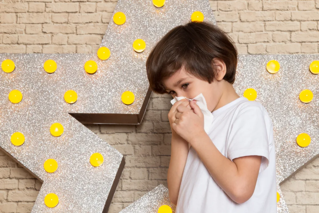 A young child sneezing indoors – a visual representation of common allergy symptoms in children. Perfect for blogs on natural remedies for allergies in kids.